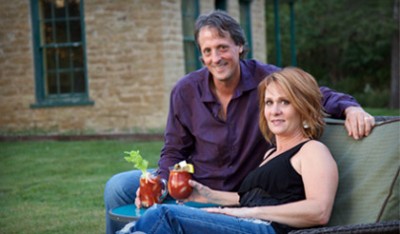 A man and woman sitting on the ground with drinks.