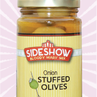 A jar of onion stuffed olives on top of a pink background.